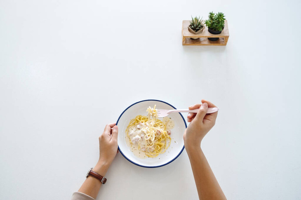Widok z góry obraz kobiety jedzącej carbonara spaghetti na stole - Zdjęcie, obraz