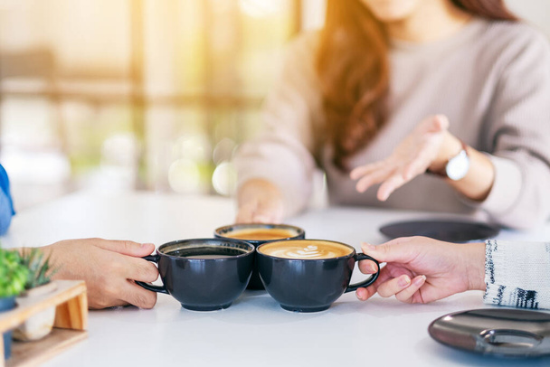 Крупный план людей, наслаждающихся разговорами во время питья и звон чашки кофе на столе в кафе - Фото, изображение