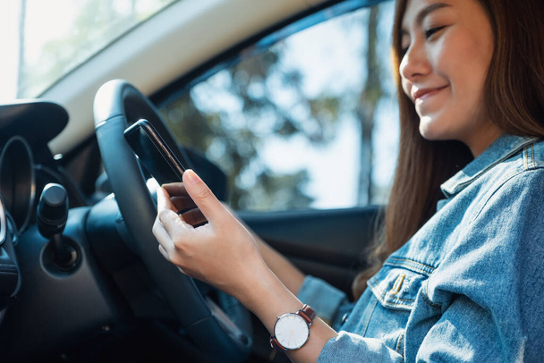 Araba kullanırken cep telefonu kullanan bir kadının yakın plan görüntüsü - Fotoğraf, Görsel