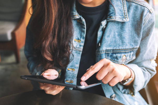 Close-up beeld van een vrouw houden en het gebruik van tablet pc tijdens het zitten in cafe - Foto, afbeelding