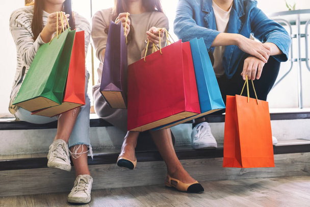 Imagen de primer plano de personas sentadas y sosteniendo bolsas de compras juntas - Foto, imagen