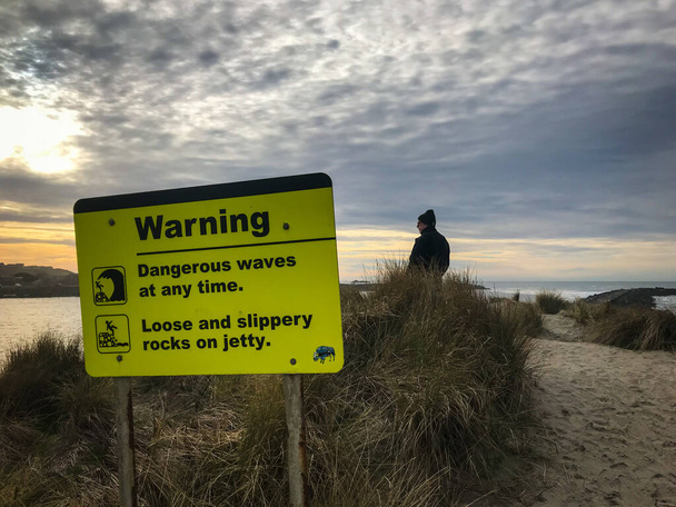 Σημάδι προειδοποίησης επικίνδυνα κύματα. Άνδρας τουρίστας στη σκηνή.  - Φωτογραφία, εικόνα
