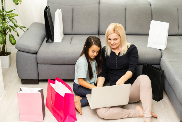 foto van gelukkig moeder en kind met laptop computer, online winkelen - Foto, afbeelding