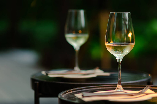 Two glasses of white wine on table with green background from garden. - Foto, immagini