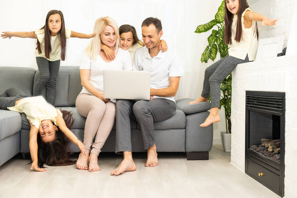 Familien kaufen online ein. Glückliche Familie lächelt, während sie auf der Couch sitzt und gemeinsam online einkauft - Foto, Bild