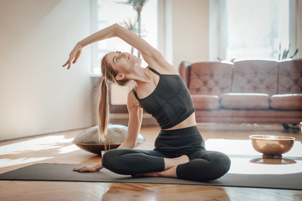 Shiny living room and relaxed woman doing yoga on mat - Photo, Image