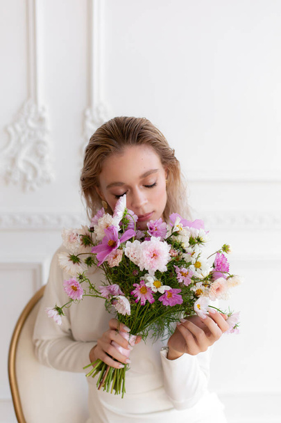 Woman in white dress holding beautiful bouquet of pink cosmos flowers. Hands with bouquet of seasonal flowers. Pink cosmos summer flowers. Wedding bouquet. - Фото, зображення
