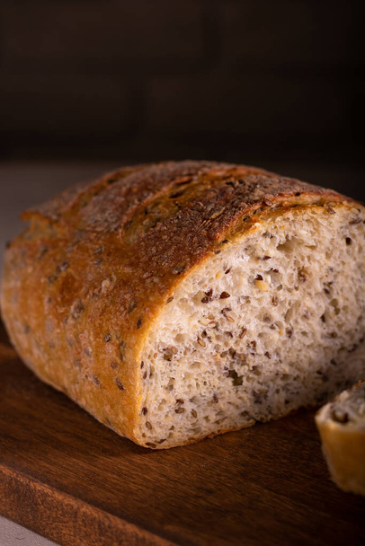 Cut freshly baked bread on a wooden board - Fotó, kép