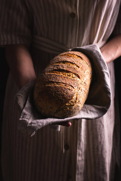Woman holding a loaf of freshly baked bread - Fotoğraf, Görsel