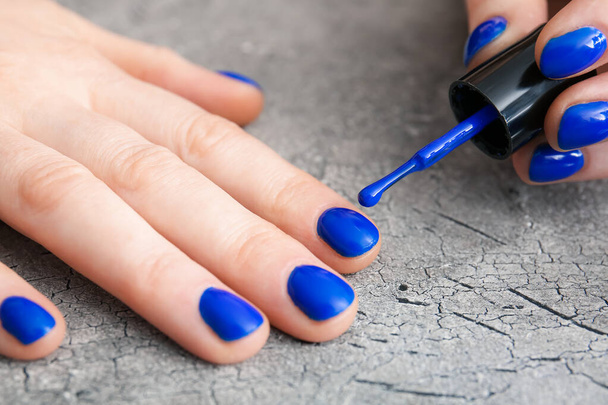 Woman doing manicure on grunge background, closeup - Foto, afbeelding