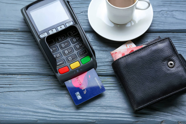 Fizetési terminál hitelkártyával, pénztárcával és csésze kávéval az asztalon - Fotó, kép