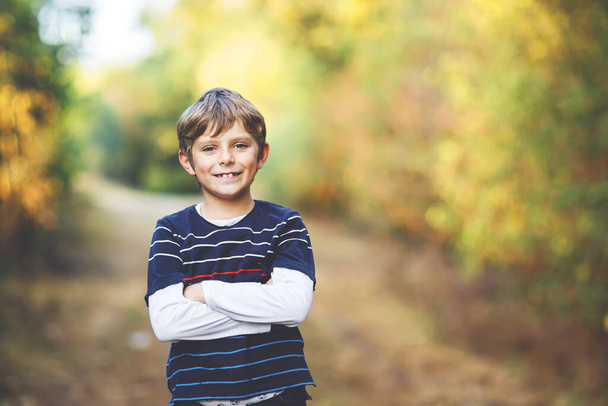 Portret van een kleine coole jongen in het bos. Gelukkig gezond kind plezier hebben op warme zonnige dag vroeg in de herfst. Familie, natuur, liefde en actieve vrije tijd. - Foto, afbeelding