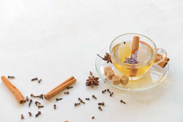 Tasty drink with cinnamon, anise and cloves in cup on light background - Photo, Image