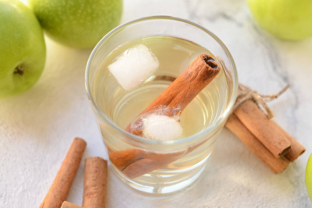 Tasty apple drink with cinnamon in glass on light background - Photo, Image