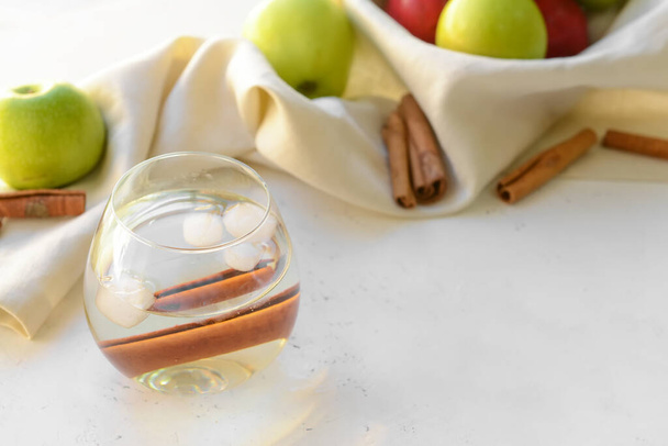 Вкусный яблочный напиток с корицей в стекле на светлом фоне - Фото, изображение