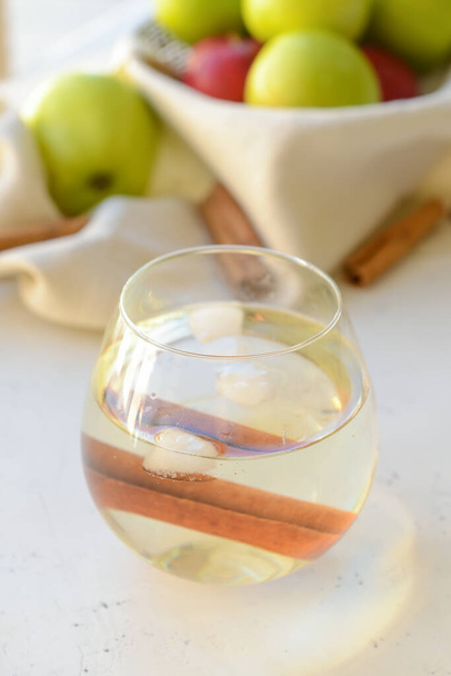 Savoureuse boisson aux pommes avec cannelle en verre sur fond clair - Photo, image