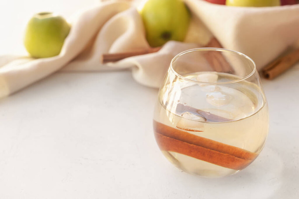 Tasty apple drink with cinnamon in glass on light background - Photo, Image