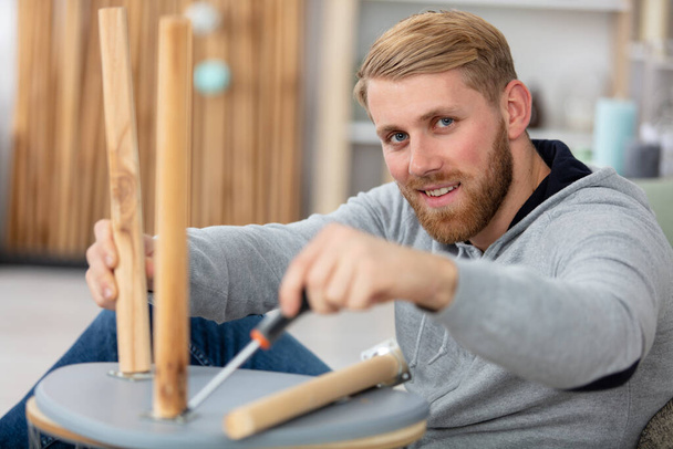 confident man assembles furniture using screwdriver - Фото, изображение