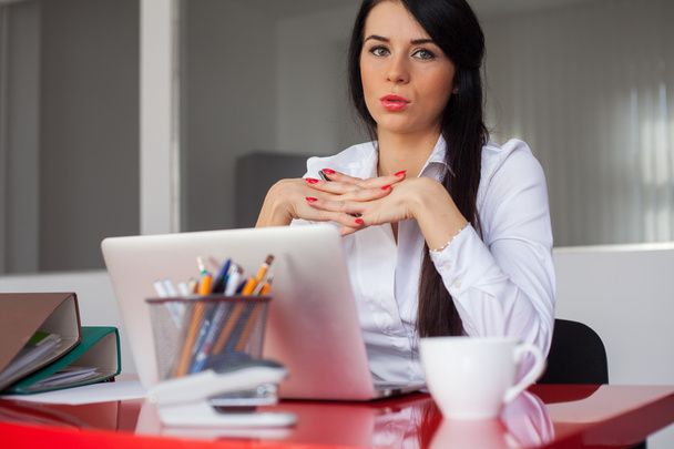 Businesswoman sitting at desk - Фото, изображение