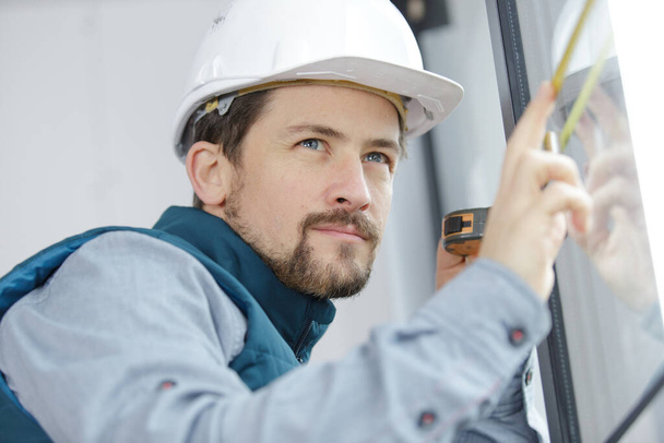 young male building contractor measuring window - Zdjęcie, obraz