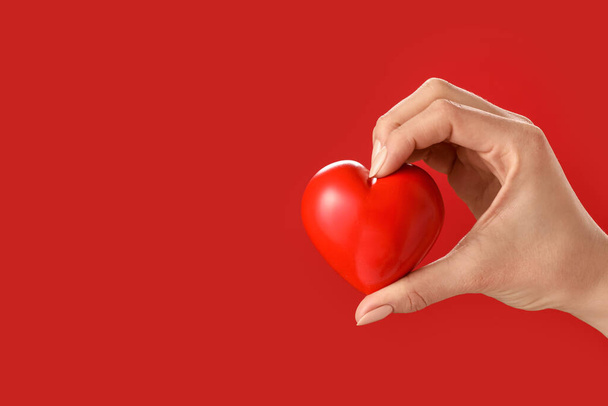 Рука с красным сердцем на цветном фоне - Фото, изображение