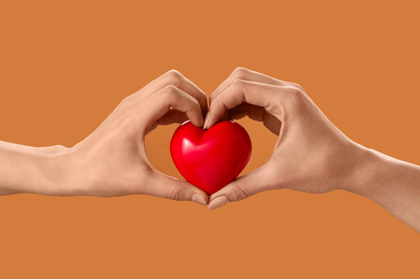 Руки с красным сердцем на цветном фоне - Фото, изображение