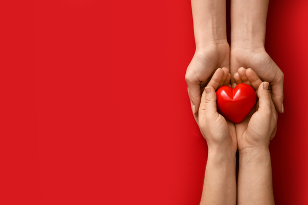 Hände mit rotem Herz auf farbigem Hintergrund - Foto, Bild