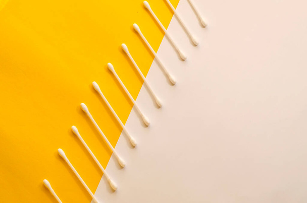 黄色と白の背景に綿棒で創造的なマルチタスクの背景。コンセプト、衛生、ボディケア、ヘルスケア. - 写真・画像