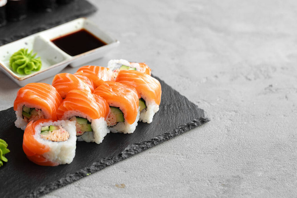 Sushi roll covered with fresh salmon served on plate - Fotografie, Obrázek