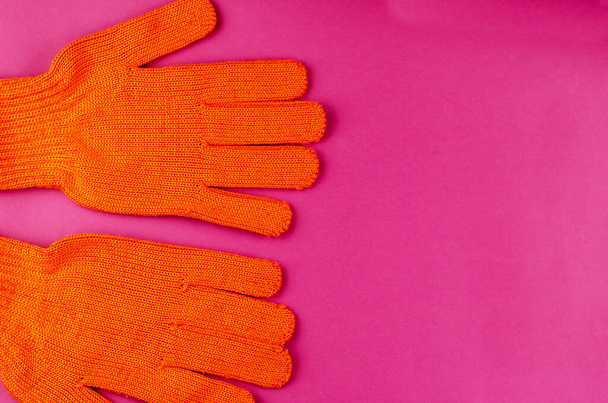 Υπηρεσίες επισκευής ή οικιακός τεχνίτης. Ένα ζευγάρι γάντια εργασίας σε μωβ φόντο. Πορτοκαλί προστατευτικά γάντια. Αντιγραφή χώρου. Επίπεδη. - Φωτογραφία, εικόνα