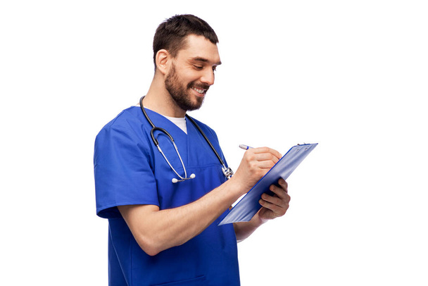 male doctor writing medical report on clipboard - Foto, afbeelding