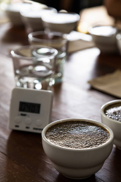 café molido con agua caliente en taza de cerámica en la mesa se está preparando para profesional Q Grader para probar e inspeccionar la calidad del café. enfoque selectivo. - Foto, Imagen