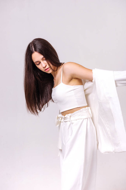 Modeporträt einer schönen Brünetten in weißer Öko-Kleidung auf weißem Hintergrund - Foto, Bild