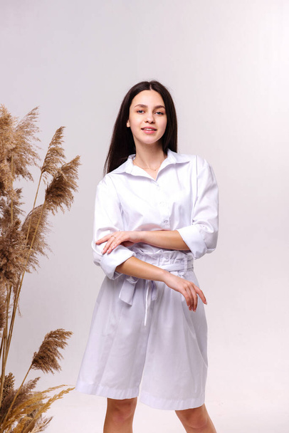 Fashion portrait of a beautiful brunette in white eco clothes on a white background - Foto, Bild