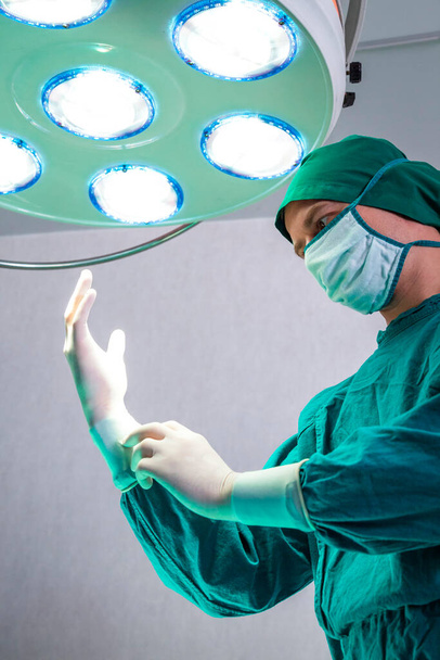 profesjonalny lekarz chirurg przygotowujący i noszący rękawice chirurgiczne na rękach przed operacją na ostrym dyżurze w szpitalu. - Zdjęcie, obraz