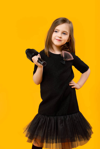 Bambina in abito nero con microfono - Foto, immagini