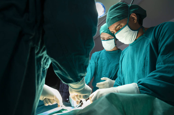 equipe médica cirúrgica profissional concentrada operando cirurgia um paciente na sala de cirurgia do hospital. conceito médico e de cuidados de saúde - Foto, Imagem