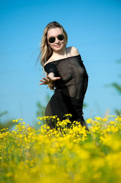 Beautiful sexy blonde girl posing in transparent blues on a flowering field - Photo, image