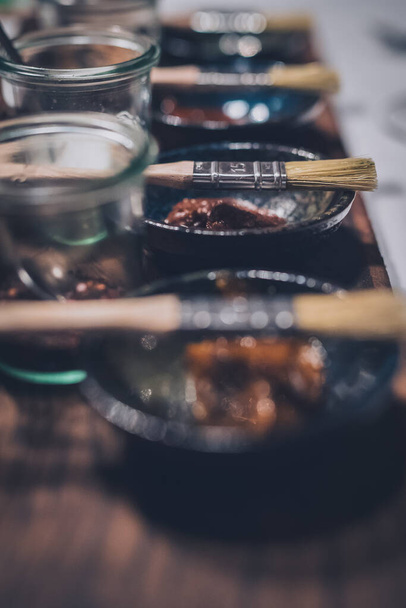 Un conjunto de pinceles con diferentes salsas en macetas de cerámica sobre una tabla de madera. Detalle en el cepillo. Cepillo utilizado para dispersar la salsa en la carne. - Foto, imagen