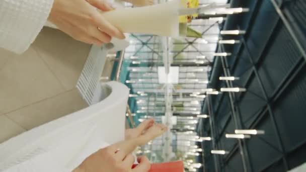 Primo piano verticale di mani irriconoscibili che tintinnano lunghi bicchieri di cocktail rinfrescanti colorati dall'acqua della piscina - Filmati, video