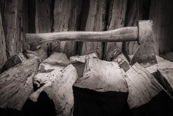 Hatchet axe and a pile of split wood logs used for fire. Concept with black and white colors- Axe viewed from the side. - Photo, Image