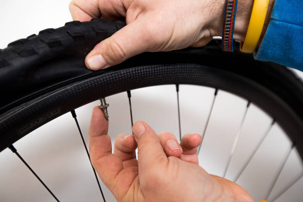 Bicycle repair - a person is inserting a washer on a presta valve on a carbon bicycle rim and tire. Finger pointing towards the valve. - Foto, Imagen