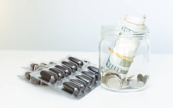 tablets, vitamins and a glass jar full of money on white background - Photo, Image