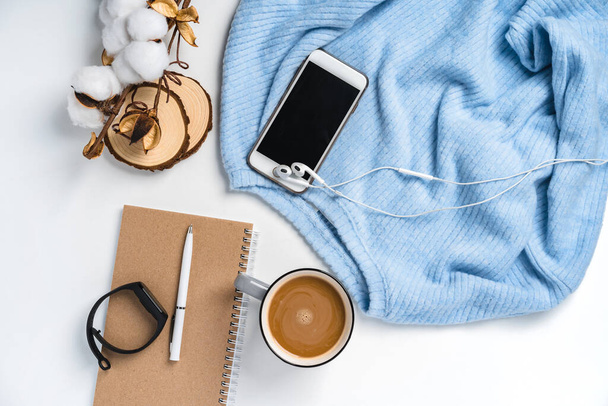  Un fond créatif moderne composé d'un pull, d'une tasse de café, d'un smartphone et d'une branche de coton. Environnement de travail à domicile confortable - Photo, image