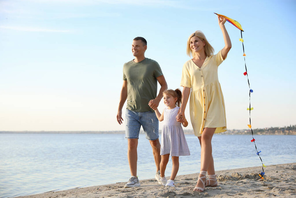 Happy parents with their child playing with kite on beach, space for text. Spending time in nature - Foto, afbeelding