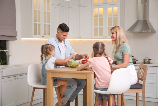 Happy family cooking together at table in modern kitchen - Foto, afbeelding