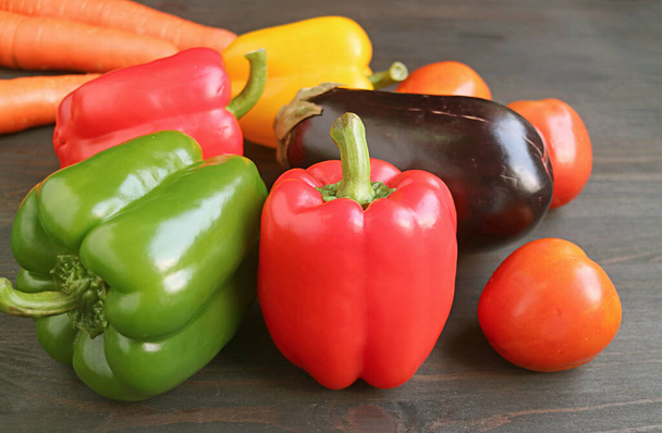 Red and green bell peppers with other colorful vegetables on dark brown wooden background - Foto, Imagen