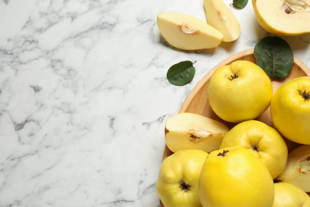 Fresh ripe organic quinces with leaves on white marble table, flat lay. Space for text - Valokuva, kuva