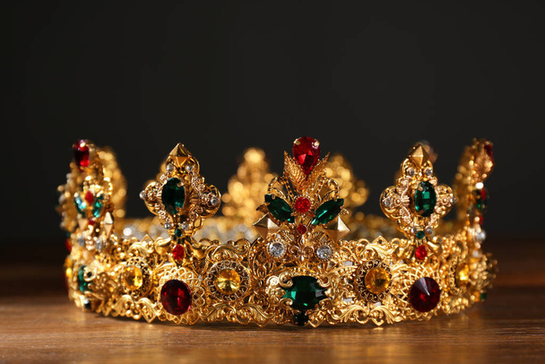 Beautiful golden crown with gems on wooden table. Fantasy item - Fotoğraf, Görsel