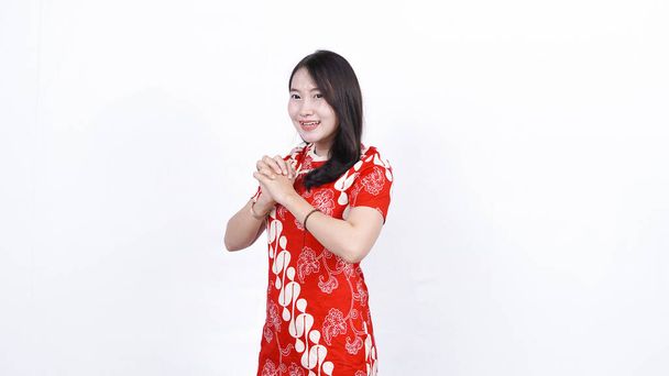 Asijská Číňanka v cheongsam šatech s blahopřejným gestem. Šťastný čínský nový rok - Fotografie, Obrázek
